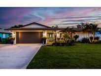 Charming home with a well-manicured lawn and tropical landscaping, illuminated by warm exterior lighting at 13168 84Th Ter, Seminole, FL 33776