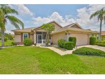 Beautiful single-story home with lush landscaping, palm trees, and a charming screened front porch at 2316 Lyndhurst Dr, Sun City Center, FL 33573