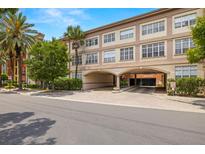Beautiful building with large windows, a parking garage, brick entrance, and tropical landscaping at 2410 W Azeele St # 214, Tampa, FL 33609