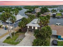 Waterfront home featuring a metal roof, mature palms, and elevated construction providing picturesque views at 3285 Minnow Creek Dr, Hernando Beach, FL 34607