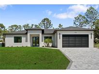 New construction featuring a manicured lawn, two-car garage, and modern gray color scheme at 3344 Lagoy St, North Port, FL 34291