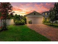 Charming single-Gathering home featuring a brick driveway, a two-car garage and sunset views at 7302 Sunshine Bridge Ave, Gibsonton, FL 33534
