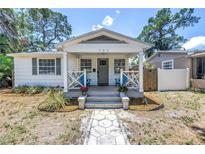 Charming home featuring a covered front porch with blue chairs and a well-maintained landscaped yard at 750 49Th N Ave, St Petersburg, FL 33703