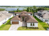 Elegant two-story home showcasing beautiful landscaping and a paver driveway leading to an attached two car garage at 8834 Sanders Tree Loop, Wesley Chapel, FL 33545