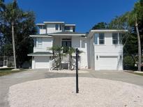 Charming two-story beach house with lush palm trees and a two-car garage in a tropical setting at 108 Peterson Ln, Palm Harbor, FL 34683