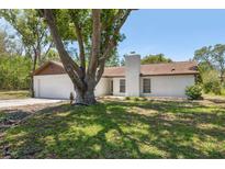 Charming single-story home features a brick exterior, chimney, attached garage, and mature trees in the front yard at 1555 Newhope Rd, Spring Hill, FL 34606