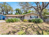 Charming single-story home featuring a well-maintained lawn and mature trees providing ample shade at 1739 Woodridge Dr, Clearwater, FL 33756
