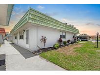 White home exterior featuring a vibrant green roof and well-maintained landscaping at 1802 Bedford Ln # 7, Sun City Center, FL 33573