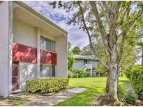 Condo exterior showcasing the front entrance, lawn, and landscaping in a well-maintained neighborhood at 1877 Pine Cone Cir, Clearwater, FL 33760