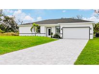 Beautiful home exterior featuring a well-manicured lawn and a paved driveway leading to an attached garage at 18773 Lake Worth Blvd, Port Charlotte, FL 33948