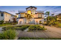 Elegant two-story home featuring lush landscaping, a symmetrical staircase entryway, and distinctive black and white accents at 6024 Kipps Colony E Dr, Gulfport, FL 33707