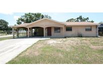Tan single-story home features a carport, beige and rock facade, and well-lit porch at 6514 La Mesa Cir, Tampa, FL 33634