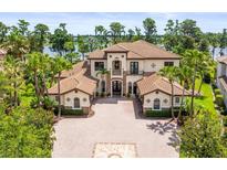 Elegant two-story home showcasing a well-manicured lawn, palm trees, and a circular driveway with a unique brick design at 17301 Ladera Estates Blvd, Lutz, FL 33548