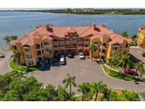 Beautiful waterfront condo building featuring a red tile roof and lush landscaping at 2773 Via Cipriani # 1310A, Clearwater, FL 33764