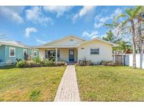 Charming one-story home with a well-manicured lawn and a brick walkway leading to a covered porch at 5713 Shore S Blvd, Gulfport, FL 33707