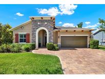 Beautiful single-Gathering home featuring a stone facade, brick driveway, and manicured lawn at 6909 Crestpoint Dr, Apollo Beach, FL 33572