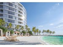 Luxury beachfront property featuring a modern condo building, sandy beach, and picturesque palm trees at 805 S Gulfview Blvd # 402B, Clearwater, FL 33767