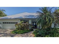 Beautiful home featuring mature landscaping, metal roof and covered front porch at 8701 Lake Calm Ln, Odessa, FL 33556