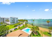 A beautiful view of the community pool with palm trees and the bay in the background at 100 Oakmont Ln # 802, Belleair, FL 33756