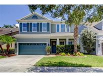 Charming two-story home with blue accents, manicured lawn, and lush landscaping at 11606 Quiet Forest Dr, Tampa, FL 33635