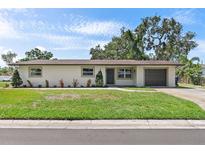 Charming single-story home boasts a well-manicured lawn, attached garage, and neutral exterior at 11764 Pinedale Ave, Seminole, FL 33772