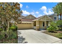 Inviting home featuring a tan exterior, two-car garage, and well-maintained lawn and landscaping at 20106 Bending Creek Pl, Tampa, FL 33647
