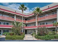 Condominium building exterior featuring red trim, balconies, tropical landscaping, and palm trees at 2073 Denmark St # 9, Clearwater, FL 33763