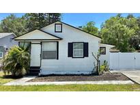Charming single-Gathering home featuring a fresh white exterior, black trim and a well-manicured front yard at 2219 Thrace St, Tampa, FL 33605