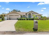 Charming single-story home featuring a two-car garage, manicured lawn, and lovely landscaping at 22852 Fern Ct, Land O Lakes, FL 34639