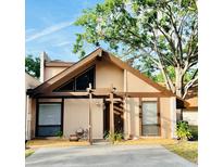 Charming tan home with a unique triangle window and lovely pergola covered front entrance at 4117 Muriel Pl, Tampa, FL 33614