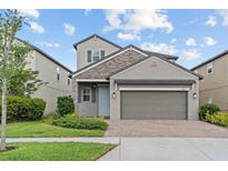 Charming two-story home featuring stone accents, a brick driveway, and well-maintained landscaping at 4345 Cadence Loop, Land O Lakes, FL 34638