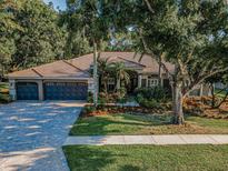 Beautiful front exterior with lush landscaping, a tile roof, and a spacious driveway with an attached three-car garage at 4962 Turtle Creek Trl, Oldsmar, FL 34677