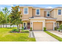 Charming townhome featuring a two-car garage, landscaped front yard, and a welcoming covered entryway at 6974 Holly Heath Dr, Riverview, FL 33578
