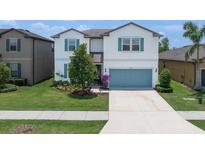 Charming two-story home boasts blue shutters, a well-manicured lawn, and an attached two car garage at 1203 Custer Bayou Street, Ruskin, FL 33570