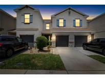 Charming two-story townhome at dusk with garage, manicured lawn, and stone accents at 12353 Bayou Flats Ln, Tampa, FL 33635