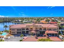 Expansive exterior shot of the red-roofed Grand Bay building with lush landscaping, a fountain, and ample parking at 3334 Purple Martin Dr # 212, Punta Gorda, FL 33950