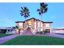 Stunning two-story home featuring a brick stairway, lush lawn, and beautiful palm trees at 514 Harbor N Dr, Indian Rocks Beach, FL 33785