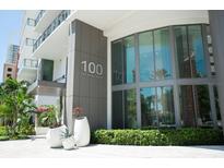 Modern building entrance with silver address numbers, large windows, and manicured hedges at 100 1St N Ave # 2207, St Petersburg, FL 33701