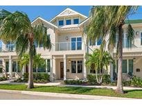 Elegant two-story townhouse featuring a balcony and lush tropical landscaping at 12 Country Club Ln, Belleair, FL 33756