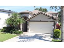 Charming home featuring a well-manicured lawn, mature palm trees, a driveway and an attached two-car garage at 12808 Killarney Ct, Odessa, FL 33556
