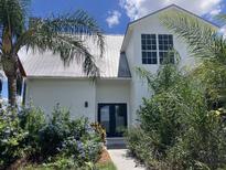 Inviting two-story home featuring a modern design, lush landscaping, and a durable metal roof at 14510 Mj Rd, Myakka City, FL 34251
