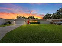 Charming single-story home featuring a well-manicured lawn, a red front door and sunset at 1546 69Th S Pl, St Petersburg, FL 33705