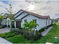Charming single-story home with a tile roof, well-manicured landscaping, and a welcoming two-car garage at 17319 Holly Well Ave, Wimauma, FL 33598