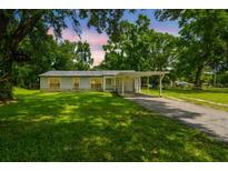 Charming single-story home with a covered carport and a well-manicured lawn nestled among mature shade trees at 25623 Inkwood Pl, Wesley Chapel, FL 33544