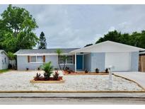 Charming single-story home featuring a blue exterior, well-manicured lawn, and a white garage door at 3401 Truman Dr, Holiday, FL 34691