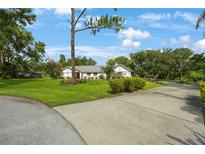 Beautifully landscaped front yard with a well-maintained lawn and a charming one-story home with a red front door at 5933 Carina Trce, Wesley Chapel, FL 33545