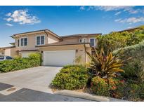 Two-story home with a two-car garage surrounded by lush landscaping including tropical plants and colorful flowers at 6627 Date Palm S Ave, St Petersburg, FL 33707