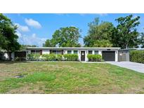 Well-manicured front lawn leading up to a charming single-story home with manicured bushes and a dark garage door at 7304 Lakeside Blvd, Tampa, FL 33614