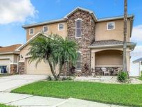Charming two-story home featuring a stone facade, well-maintained lawn, and inviting covered porch with seating at 10713 Shady Preserve Dr, Riverview, FL 33579