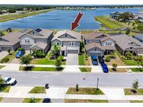 Aerial view of two-story gray home with manicured lawn and lake view at 11320 Chilly Water Ct, Riverview, FL 33569
